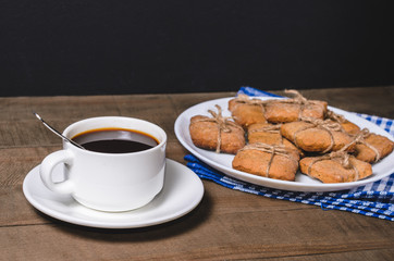 Black coffee in a white cup on a blue napkin and homemade cookies.