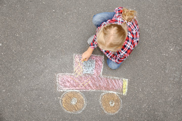 Fototapeta premium Little girl drawing car with chalk on asphalt