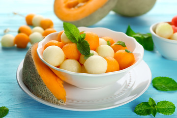 Plate with fresh melon balls on table