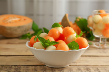 Plate with fresh fruit balls on table