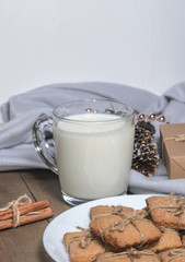 A cup of milk, cinnamon sticks and homemade cookies in a Christmas decor.