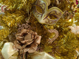 Dettagli di un albero di natale color oro con una rosa ed una maschera