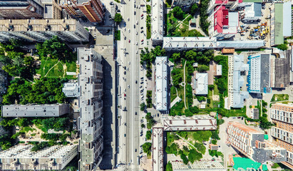 Fototapeta premium Aerial city view with crossroads and roads, houses, buildings, parks and parking lots, bridges. Helicopter drone shot. Wide Panoramic image.