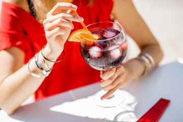 Woman holding a glass with Sangria, traditional spanish alcohol beverage made of wine, sitting...