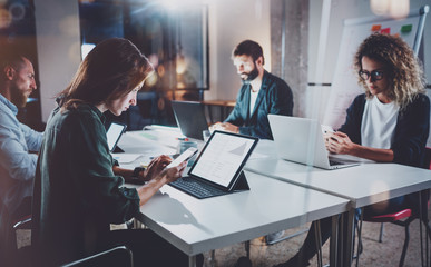 Working process photo.Group of young coworkers working together at night modern office loft.Teamwork concept.Blurred background.Horizontal.