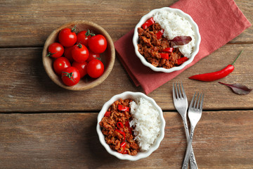 Chili Con Carne with rice in bowls on wooden background