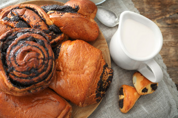 Tasty pastries with poppy seeds on wooden plate