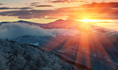 Panoramic view of winter mountains at sunrise. Landscape with foggy hills and trees covered with...