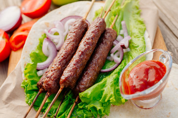 Fast food. Eastern food. Shish kebab, lyulya-kebab, shaverma, pita gyros. Dishes of oriental cuisine lying on pita bread and decorated with greens and vegetables, sauces and French fries. 