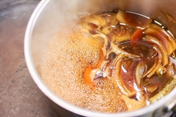 Flavor shank of lamb boiling in saucepan. Slow cooked leg of lamb with broth in casserole close up. Delicious food of european restaurant.