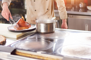 Fresh boiled shank of lamb. Male chef putting on large piece of boiled lamb shank on white kitchen paper.