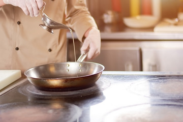 Chef pouring oil in frying pan. Male chef in gloves going to fry duck breast. Cook preparing meat.