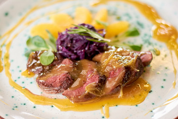 Appetizing duck breast with orange sauce. Duck breast beautifuly served on plate close up. Delicious dinner at restaurant.