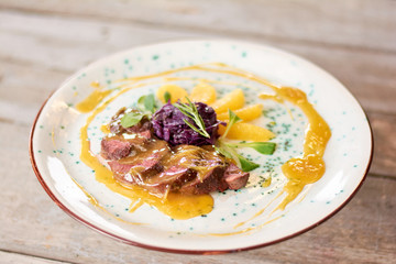 Duck breast with orange sauce. Beautifuly served duck breast on plate. Delicious dinner at restaurant.