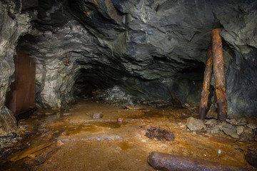 Underground abandoned old mine shaft iron copper gold ore tunnel gallery with wooden stands timbering