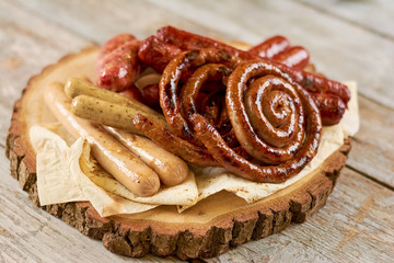 Grilled appetizing sausages on platter. Octoberfest traditional food. Tasty grilled sausages, german food. Delicious fried sausages on board.