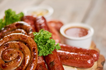 Grilled sausages on blurred background. Appetizing grilled sausages with parsley close up.