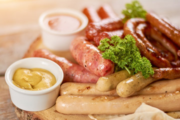 Grilled sausages with parsley and mustard. Appetizing assortment of grilled sausages with mustard and parsley. Delicious restaurant food.