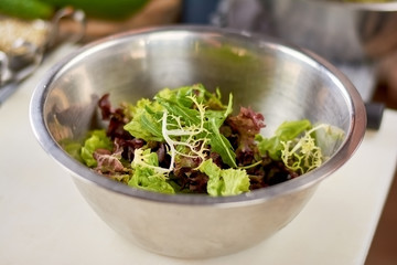 Mixed salad leaves in stainless bowl. Fresh mix of green and purple salad on table close up. Dish cooking at restaurant.