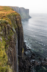 Mealt Falls and Kilt Rock cliff between Portree and Staffin, in the Isle of Skye, Scotland. The waterfall plunges into the sea with the basalt formation resembling a skirt in the background.