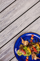 Warm salad with quail meat and green lettuce. Appetizing salad on restaurant table and copy space, top view.