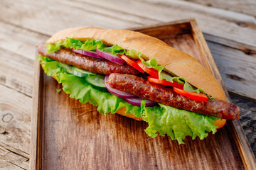 Oktoberfest. German hot dog with grilled sausages, onions and vegetables. French roll with grilled sausages from lamb.