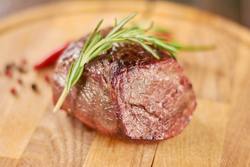 Delicious beef steak on wooden platter. Grilled beef steak with rosemary on wooden board.