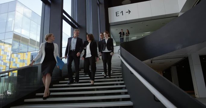 Modern business people walking on stairs in glass hall of office building