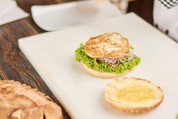 Cooking burger with chicken meat. Preparing of delicious chiken burger with lettuce and tomato. Appetizing american food.