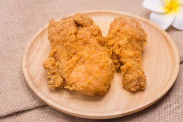 Delicious fried chicken in wooden dish on sackcloth with plumeria flower.