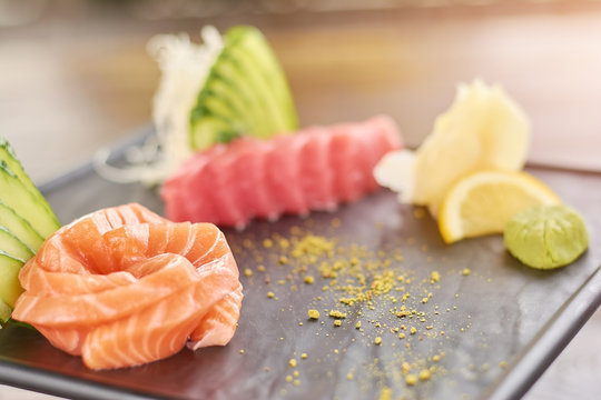 Raw salmon sliced on black plate. Salmon and tuna sashimi set. Delicious food of japanese culture.