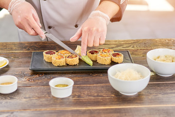 Chef serving sushi set with wasabi. Cook adding wasabi to sushi set on plate. Sushi preparation at kitchen.