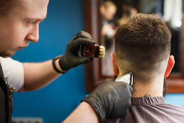 Naklejka premium Man getting haircut by hairstylist at barbershop