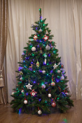 Artificial Christmas tree in front of the window in the apartment 