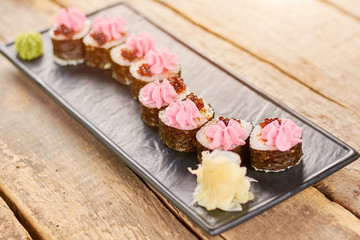 Beautifully decorated sushi rolls on plate. Appetizing japanese sushi rolls on vintage wooden table. Delicious japanese food.