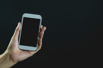 Woman hand holding smart phone isolated on dark background.
