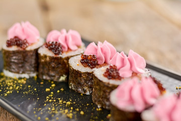 Nori sushi rolls with cream on plate. Sushi roll with salmon and avocado served with caviar and cheese cream. Tokobana sushi roll.