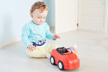 Cute little boy playing with a toy car. Happy kid sitting in studio