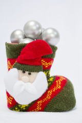 Red and green Santa's boot on the white background with Christmas white brilliant  balls. Decoration of Santa Claus background. Copy space. Concept of Xmas and new year holidays.