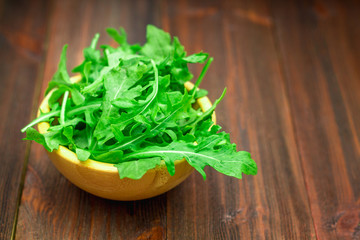 Fresh juicy leaves of arugula on a brown wooden table.