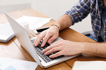 Hands typing on a laptop in modern office, closeup