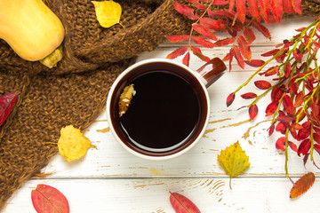 Mug of hot coffee in autumn setting on a wooden table with a knitted scarf, sweater. Comfort, warmth, cozy.