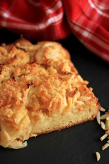 Fresh homemade Apple Pie with almond slivers and red kitchen towel on black background