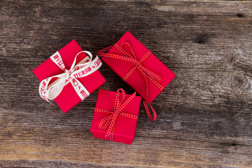 Christmas gift giving - pile of wrapped in red paper christmas gift boxes on wooden background