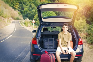 child with suitcases and car prepared for road travel
