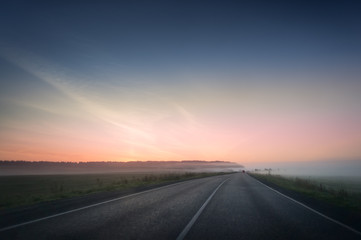 Fototapeta na wymiar summer rural landscape with blue and red sky, fog and the road. sunrise