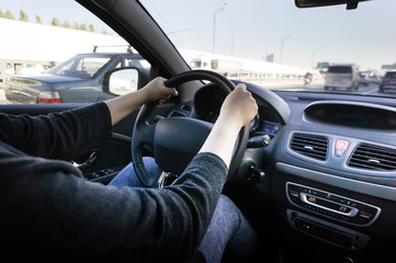 Woman's hands on the steering wheel of the car.