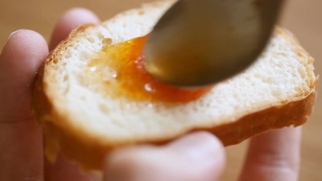 Spreading fruit jam on bread slice