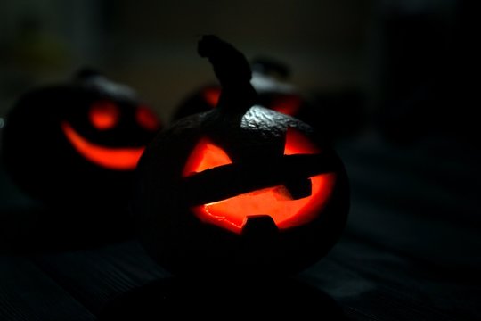 Halloween Jack-o-lantern pumpkins on a dark wooden background