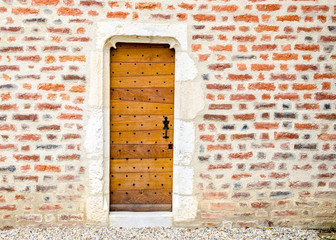 little wooden door of a little church at left of a brick wall